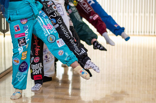 Eriv&amp;amp;amp;amp;auml;risiin opiskelijahaalareihin pukeutuneet opiskelijat ojentavat jonossa jalkaa balettitunnilla.